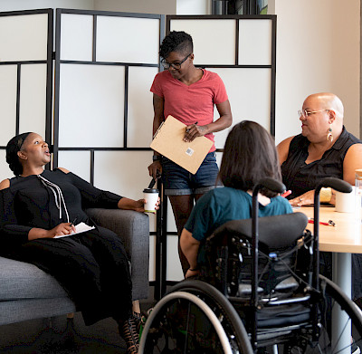 A meeting of students and staff who sit around a table.